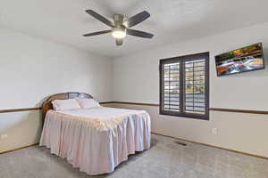 Carpeted bedroom with a ceiling fan and a textured ceiling