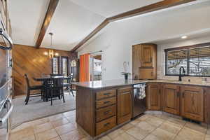Kitchen featuring dark stone counters, wood walls, a peninsula, wood finish cabinets, and light colored carpet
