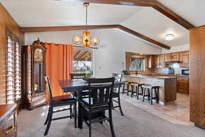 Dining space with light carpet, a chandelier, lofted ceiling with beams, and light tile patterned flooring