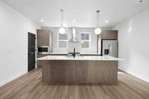 Photo of finished unit - Photo of finished unit - Kitchen featuring modern cabinets, light stone counters, pendant lighting, and an island with sink