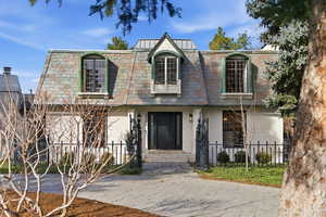 View of front property with mansard roof and a fenced front yard