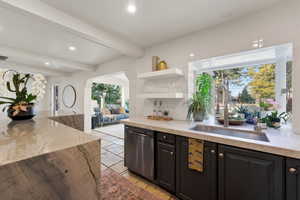 Kitchen with light stone counters, stainless steel dishwasher, open shelves, recessed lighting, and beam ceiling