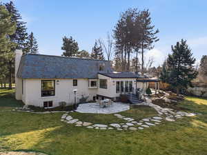 Rear view of house featuring a patio, a chimney, and a high end roof