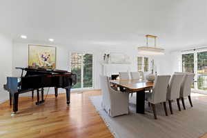 Dining space with light wood-style flooring, a warm lit fireplace, and recessed lighting