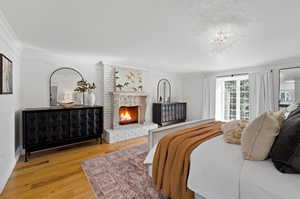 Bedroom featuring hardwood / wood-style floors, a fireplace, and ornamental molding