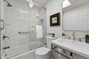Bathroom with combined bath / shower with glass door and tasteful backsplash