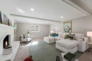 Living area with carpet floors, beam ceiling, recessed lighting, and a fireplace
