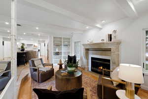 Living room featuring beam ceiling, a glass covered fireplace, recessed lighting, and light wood-type flooring
