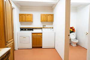 Laundry room featuring cabinet space, washer and clothes dryer, and finished concrete floors