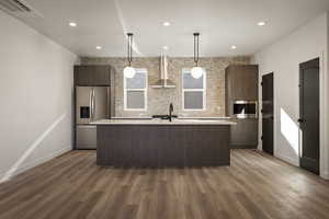 Kitchen with modern cabinets, stainless steel fridge with ice dispenser, a kitchen island with sink, and hanging light fixtures