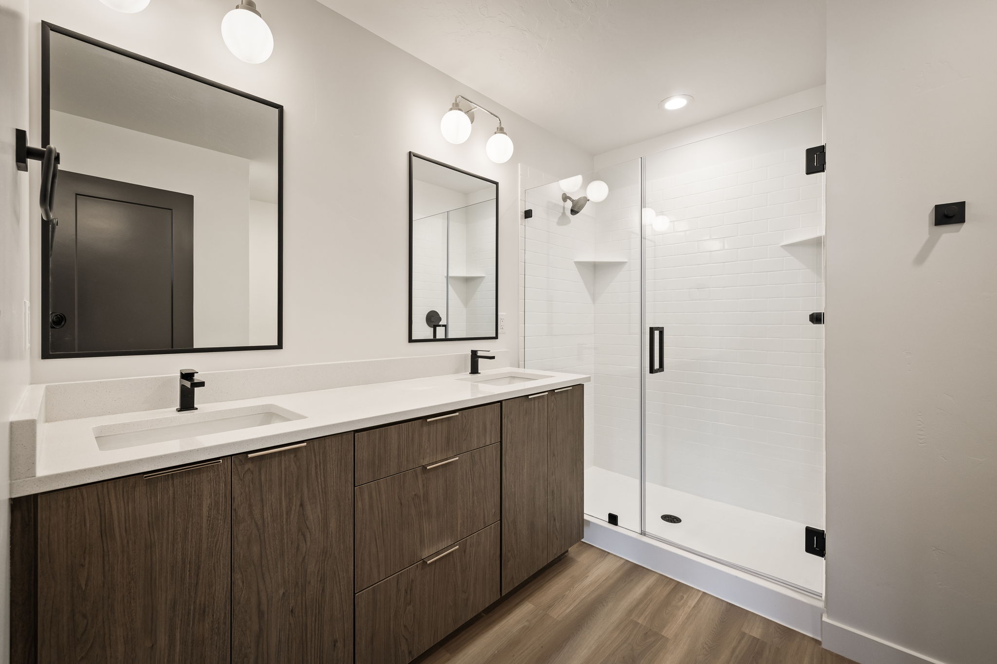 Full bath with a stall shower, dark wood finished floors, double vanity, and recessed lighting
