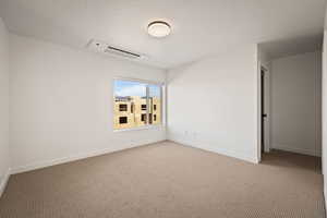 Carpeted spare room with cooling unit and baseboards