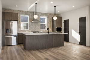 Kitchen with stainless steel appliances, modern cabinets, hanging light fixtures, and dark wood-style flooring