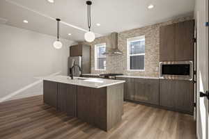 Kitchen with pendant lighting, dark wood-style flooring, an island with sink, and stainless steel appliances