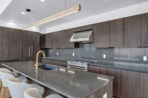 Kitchen with modern cabinets, extractor fan, stainless steel range, a breakfast bar, and dark wood finish cabinets