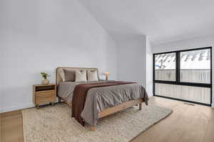Bedroom with light wood-style flooring and lofted ceiling