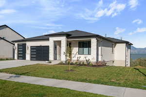 View of front of property with stone siding, a front yard, a garage, and covered porch