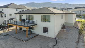 Back of house with a shingled roof, a deck with mountain view, stucco siding, and a residential view