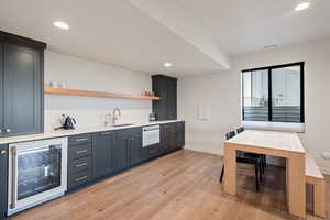 Indoor wet bar with open shelves, wine cooler, light wood-type flooring, recessed lighting, and light stone countertops