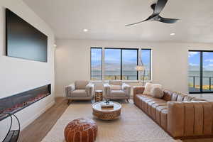 Living room with ceiling fan, wood finished floors, a glass covered fireplace, plenty of natural light, and recessed lighting
