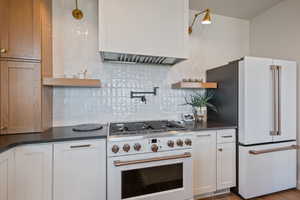 Kitchen featuring white appliances, open shelves, white cabinets, and backsplash