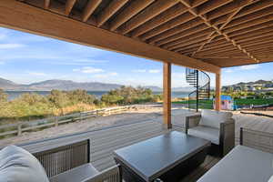 Wooden terrace featuring outdoor seating, a patio area, and a water and mountain view