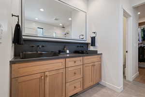 Bathroom featuring double vanity, a walk in closet, recessed lighting, tiled shower, and decorative backsplash