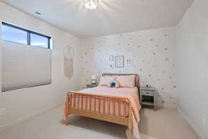 Carpeted bedroom with baseboards and wallpapered walls