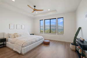 Bedroom featuring a mountain view, hardwood / wood-style floors, ceiling fan, recessed lighting, and a tray ceiling