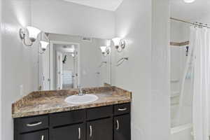Full bathroom featuring vanity, a textured wall, and shower / tub combo