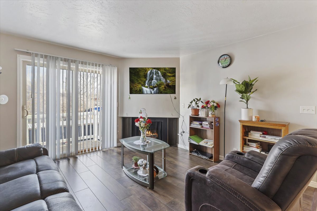 Living area with wood-style flooring and a warm lit fireplace