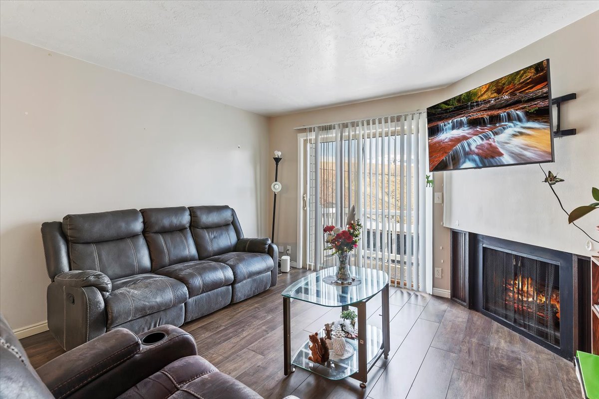 Living area with a lit fireplace, wood-style finished floors, and a textured ceiling