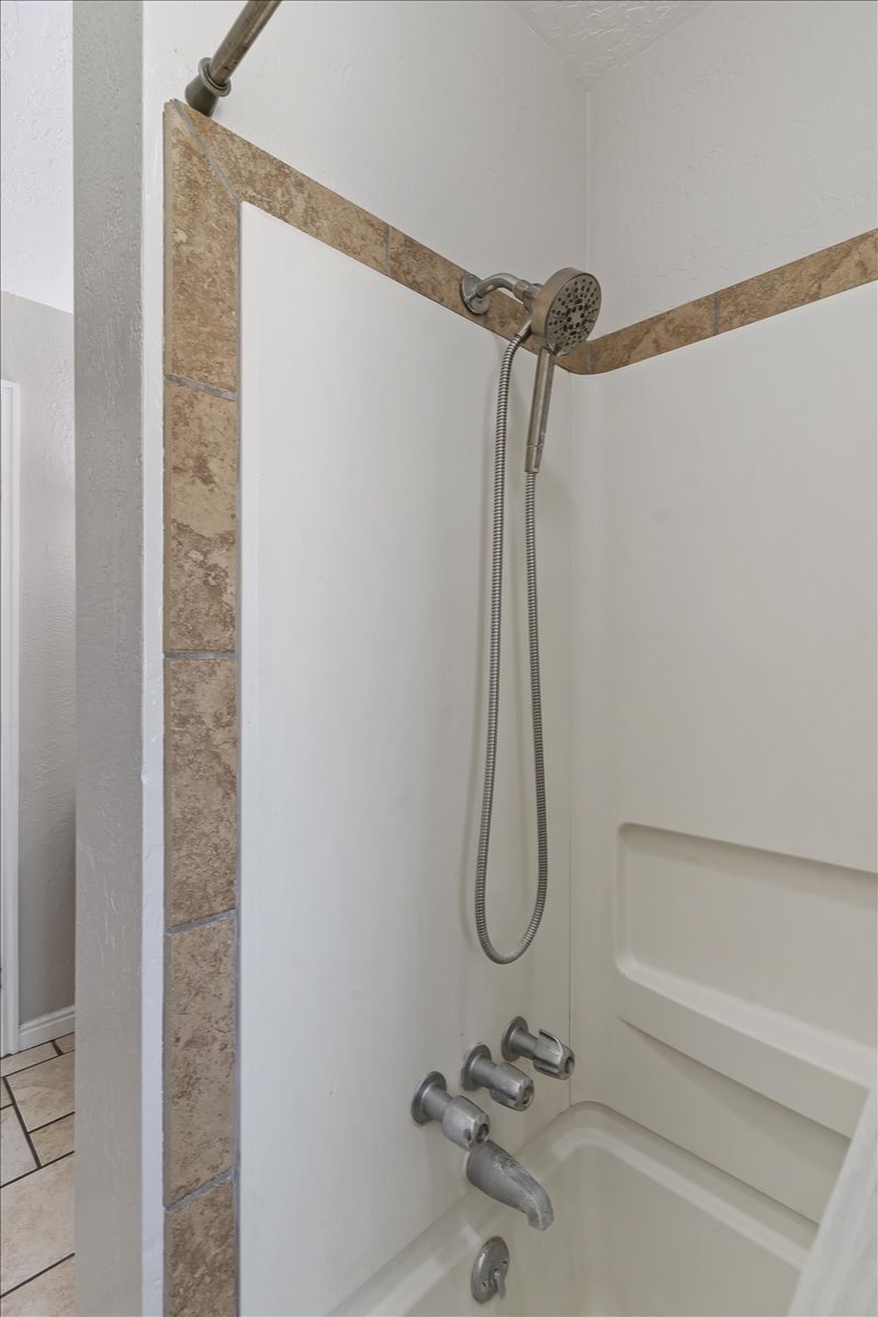 Bathroom with bathing tub / shower combination and light tile patterned floors
