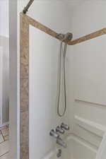 Bathroom with bathing tub / shower combination and light tile patterned floors