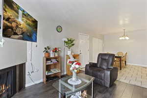 Living area with a lit fireplace, hanging lights, and wood-style finished floors