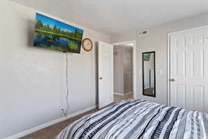 Carpeted bedroom with baseboards and a textured ceiling