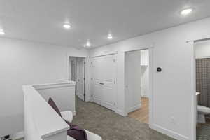 Unfurnished room featuring light carpet, recessed lighting, and an upstairs landing