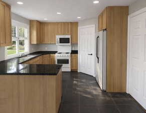 Kitchen featuring white appliances, dark stone countertops, a peninsula, recessed lighting, and dark tile patterned floors