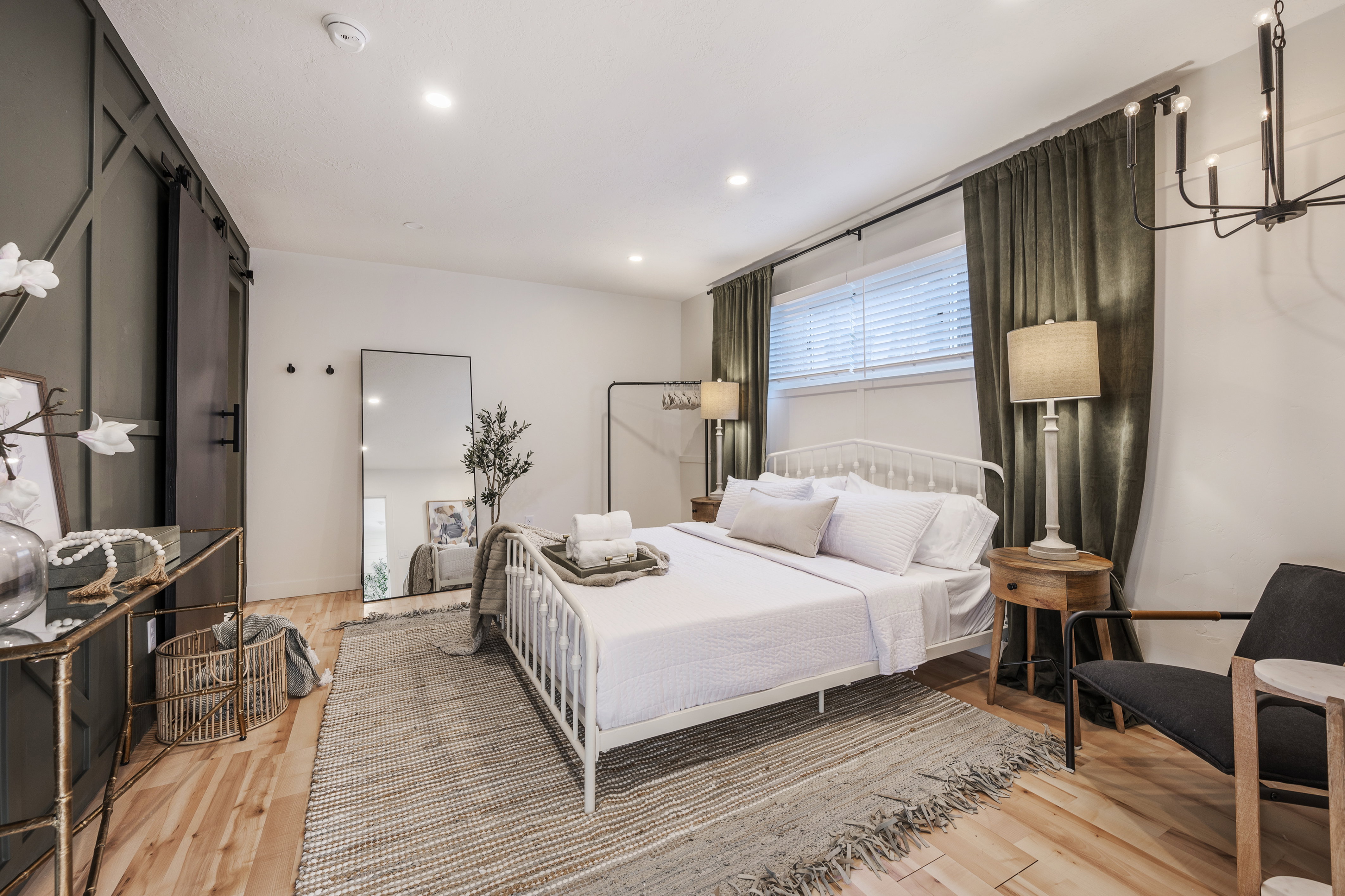 Bedroom featuring a barn door, light wood finished floors, and a chandelier