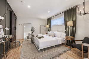 Bedroom featuring a barn door, light wood finished floors, and a chandelier