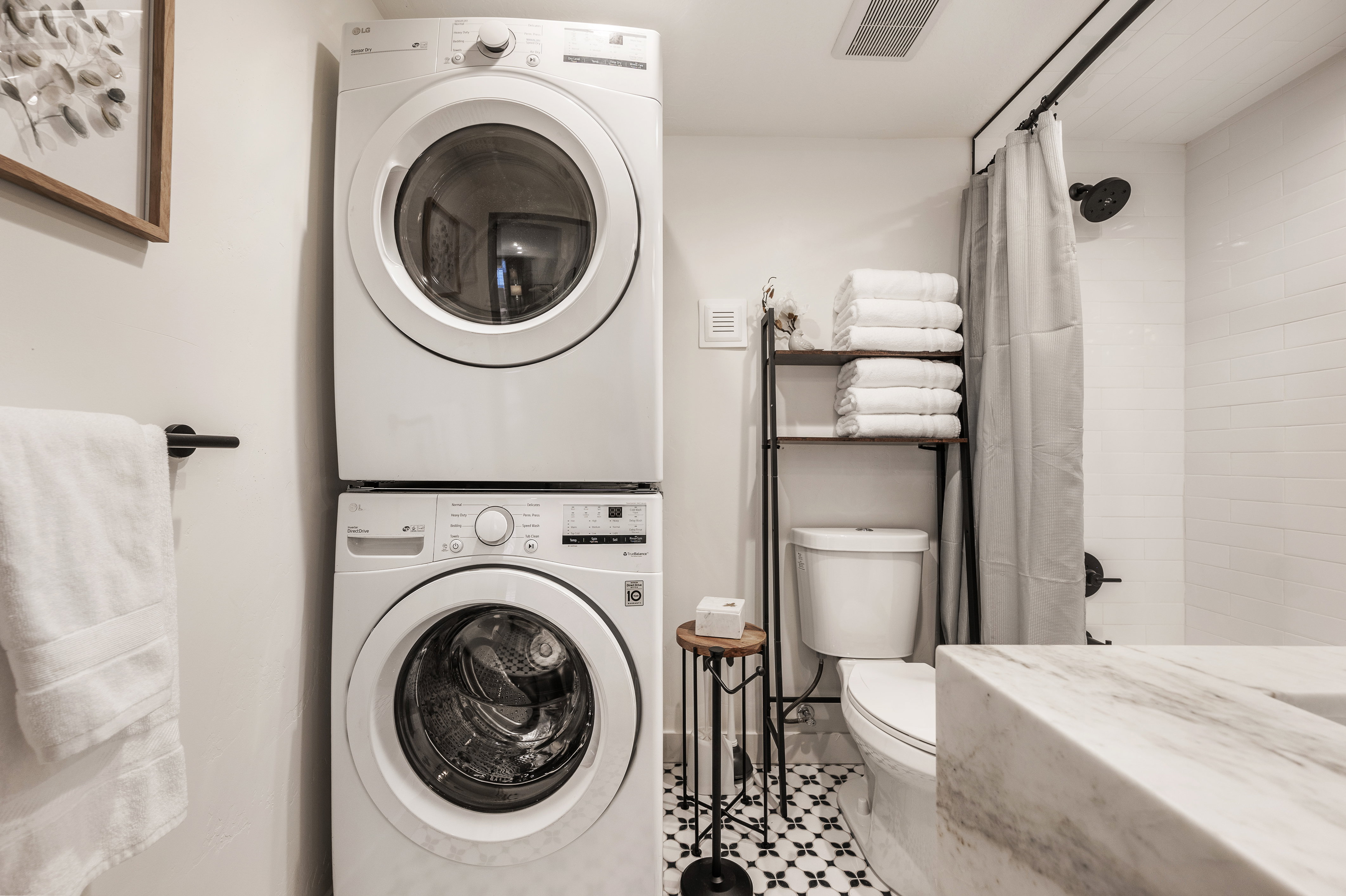 Full bath with stacked washing machine and dryer, shower / bathtub combination with curtain, and tile patterned flooring