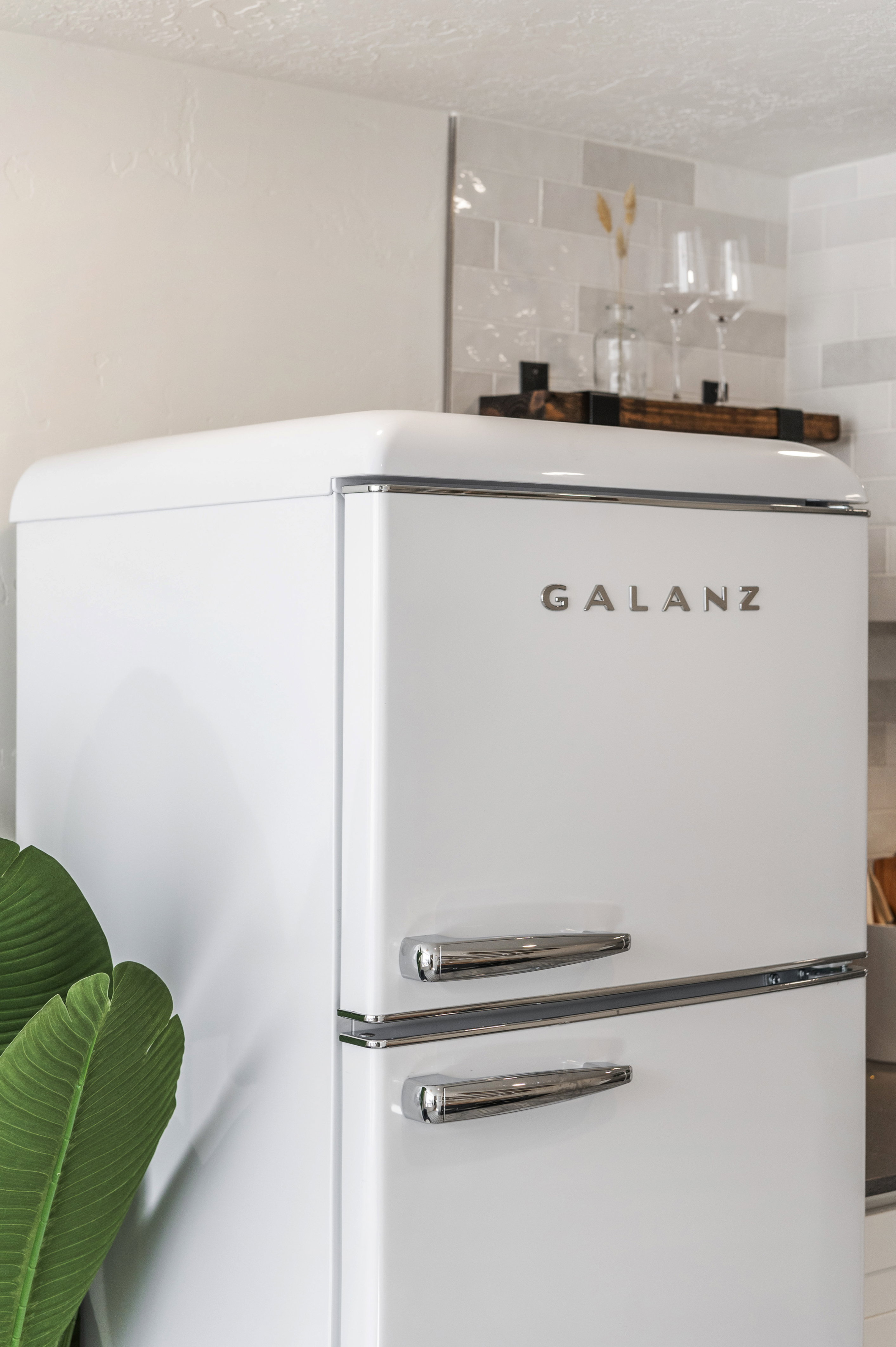 Kitchen view of freestanding refrigerator, a textured ceiling, and white cabinets