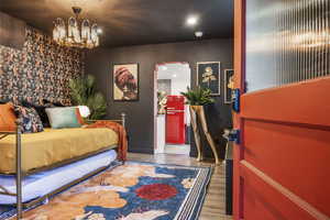 Bedroom with suspended lighting, light wood-style floors, arched walkways, and freestanding refrigerator