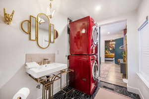 Ensuite bathroom with stacked washer and clothes dryer, recessed lighting, dark tile patterned flooring, and tasteful backsplash