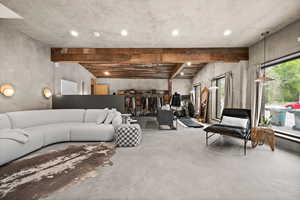 Living area with finished concrete floors, beam ceiling, and recessed lighting