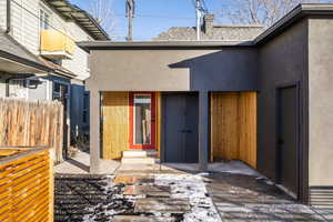 View of exterior entry with stucco siding, a chimney, and a shingled roof