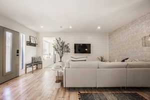 Living area featuring light wood-style flooring, recessed lighting, and wood walls