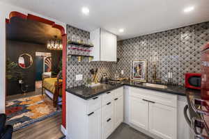 Kitchen featuring white cabinets, dark stone countertops, open shelves, and decorative backsplash