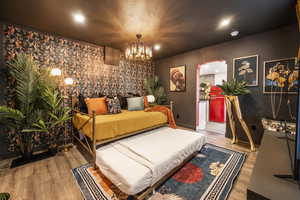 Bedroom featuring wood finished floors, a chandelier, and arched walkways