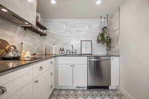 Kitchen with open shelves, white cabinets, dishwasher, dark stone counters, and recessed lighting